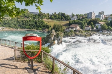 Eine Aussicht auf den Rheinfall mit einem "Grand Tour of Switzerland" Schild im Vordergrund.
