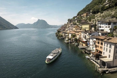 Un bellissimo paesaggio lacustre con case colorate sulla riva e una nave sull'acqua.