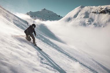 Skier on a snow-covered slope in the mountains in sunshine.