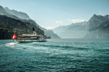 A steamship on a lake with mountains in the background.