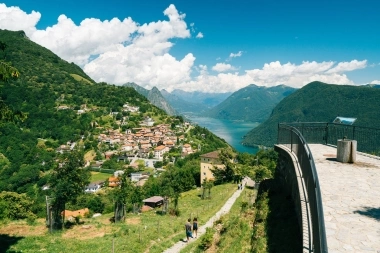A view of a village in the mountains with a lake in the background, taken from an elevated platform.