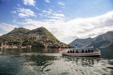 Un bateau sur un lac avec des montagnes en arrière-plan sous un ciel bleu.