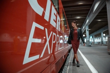 Eine Frau geht lächelnd neben einem roten Zug mit der Aufschrift „EXPRESS“.