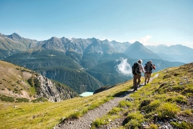 Deux randonneurs sur un sentier de montagne avec vue sur un paysage montagneux.