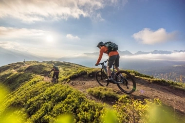 Due mountain biker su un sentiero di montagna al tramonto.