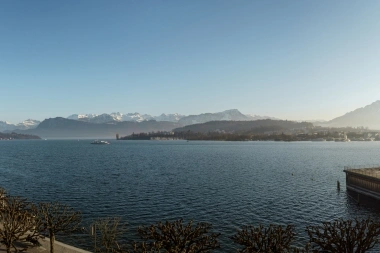 Expansive view over a lake with snow-covered mountains in the background.