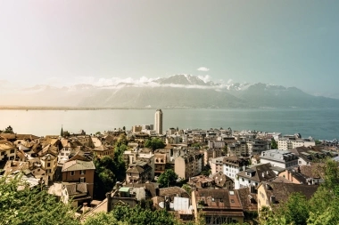 City view by the lake with mountains in the background.