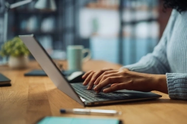 Eine Person tippt auf einer Laptop-Tastatur in einem gemütlichen Raum.