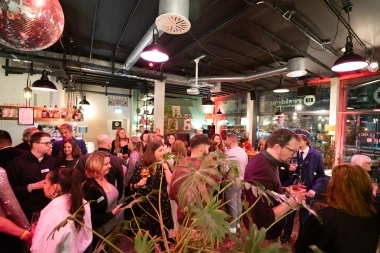 Eine GruppeUn groupe de personnes lors d'un événement dans un bar avec une boule disco et des plantes au premier plan.