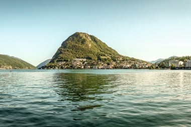 Panoramabild eines Sees mit einem promienten Berg im Hintergrund.