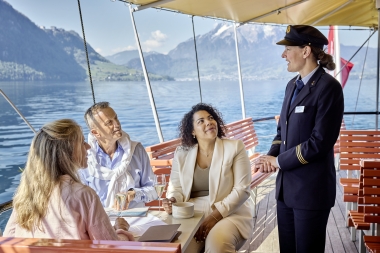 Travellers on a steamboat with Lake Lucerne and mountains in the background