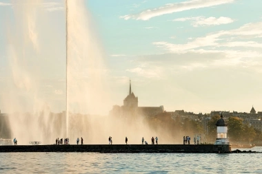 Jet d'eau de Genève avec silhouettes de personnes sur le ponton.