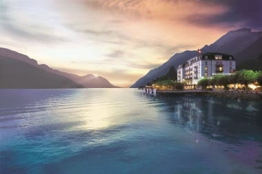 Aerial view of a city by a lake with mountains in the background.