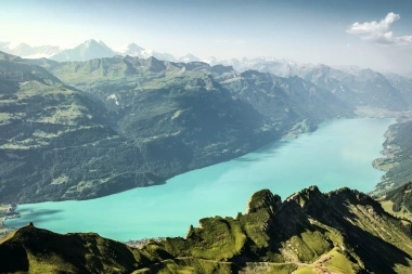 The view from the Brienzer Rothorn over the turquoise Lake Brienz, with numerous mountain peaks in the background.