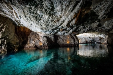 Ein unterirdischer See mit blauem Wasser in einer Höhle.