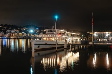 Beleuchtetes Schiff der SGV bei Nacht auf dem Vierwaldstättersee, im Wasser spiegeln sich die Lichter.