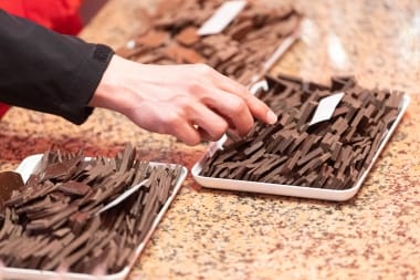 Chocolate tasting – a hand reaches for a selection of chocolate pieces.