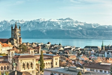 The old town of Lausanne, with Lake Geneva and a mountain panorama in the background.