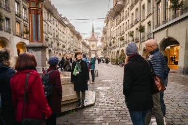 A tour guide is speaking to a group in Bern’s Old Town, with the Zytglogge clock tower visible in the background.