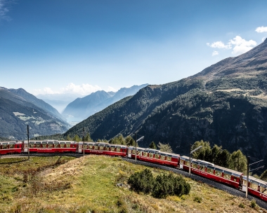 A red train travels through a mountain landscape.