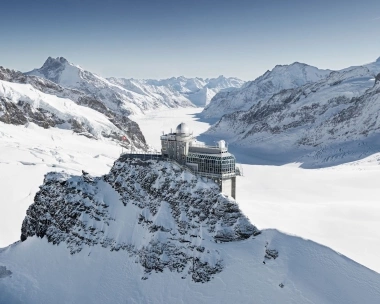 Observatoire sur une montagne enneigée avec un paysage alpin à couper le souffle en arrière-plan.