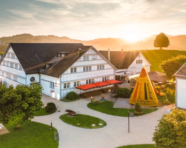Landschaft mit traditionellem weissen Gebäude, einem Restaurant, und Wiesen im Sonnenuntergang.