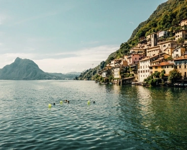 A beautiful lakeside landscape with houses on the slope and a mountain in the background.