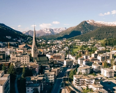 A city in a valley surrounded by mountains; centrally, a church tower.