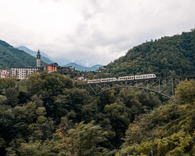 A mountain city with a train crossing a bridge.