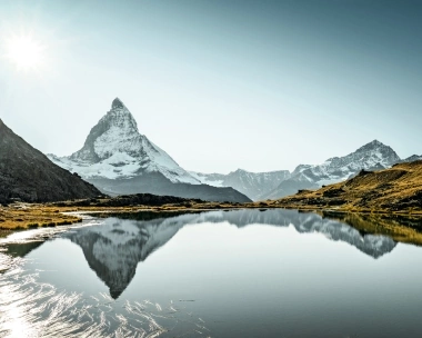 A mountain landscape with a snow-covered peak reflected in a calm lake.