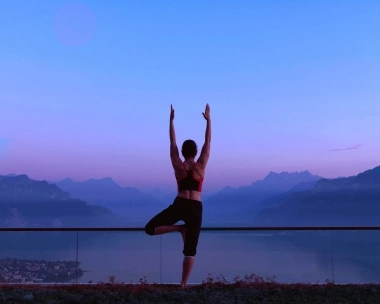 A person doing yoga in front of a mountain backdrop at sunset.