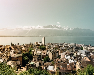 Stadtansicht am See mit Bergen im Hintergrund.