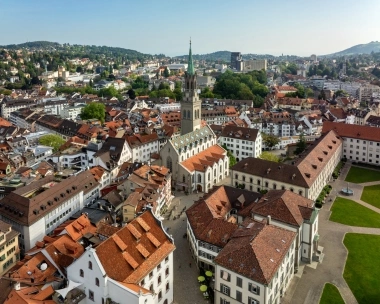 Aerial view of a historic city with a church and red tiled roofs.