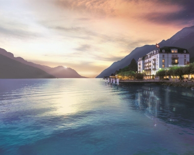 Vue aérienne d'une ville au bord d'un lac avec des montagnes en arrière-plan.