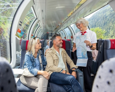 A tour guide shows travellers information on a map in the panorama carriage.