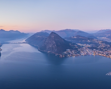 Vista su una città in riva al lago, circondata dalle montagne nell’atmosfera serale.